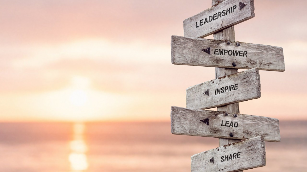 leadership empower inspire lead share text engraved on wooden signpost at the beach during sunset. By Jon Anders Wiken [Adobe Stock Photos]